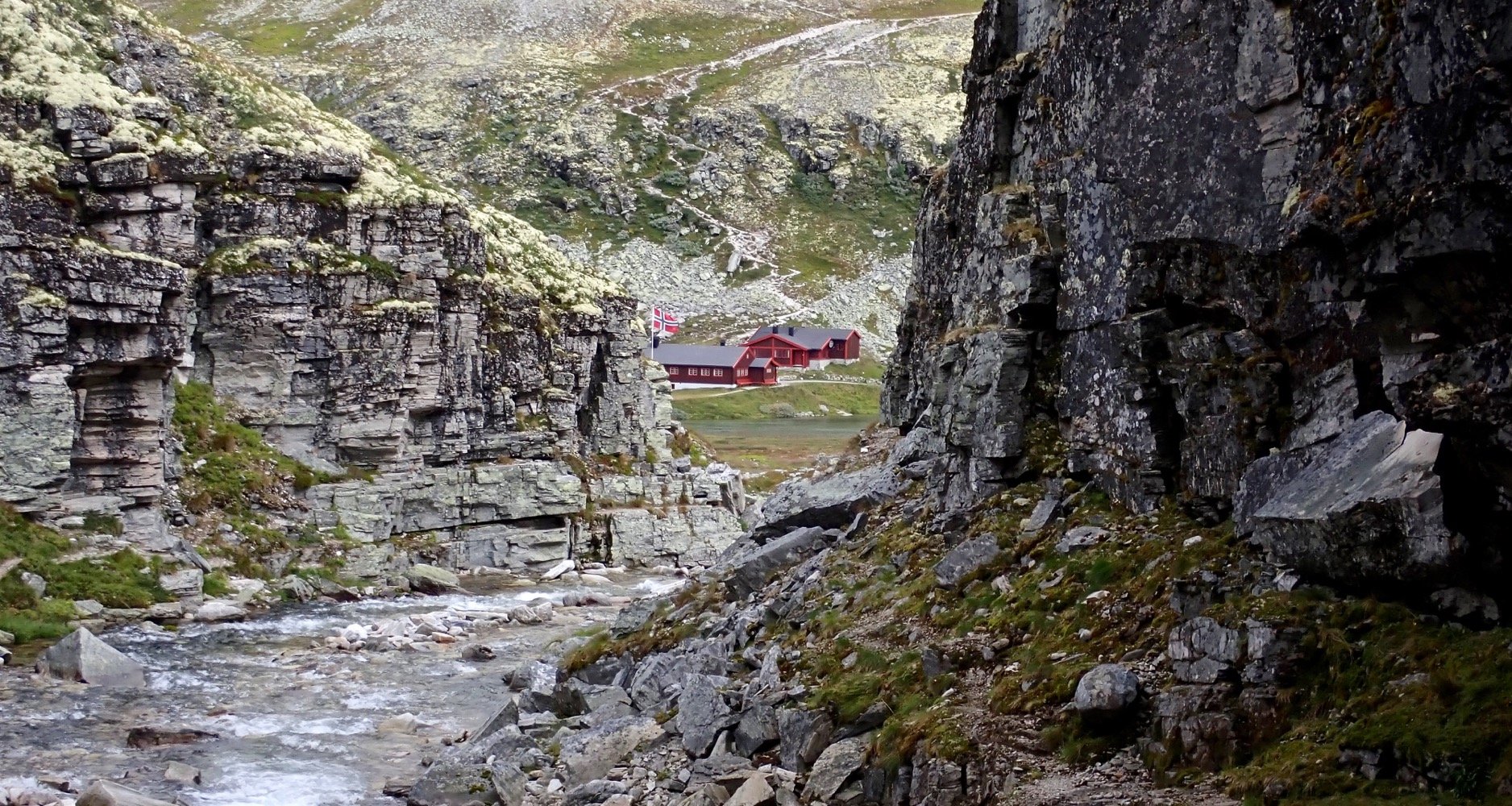 Punainen retkeilymaja näkyy kahden kalliojyrkänteen välistä. 