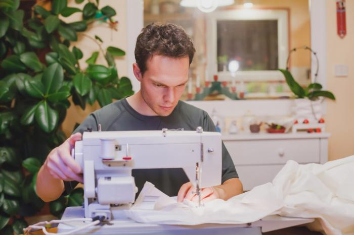 man sewing in his home