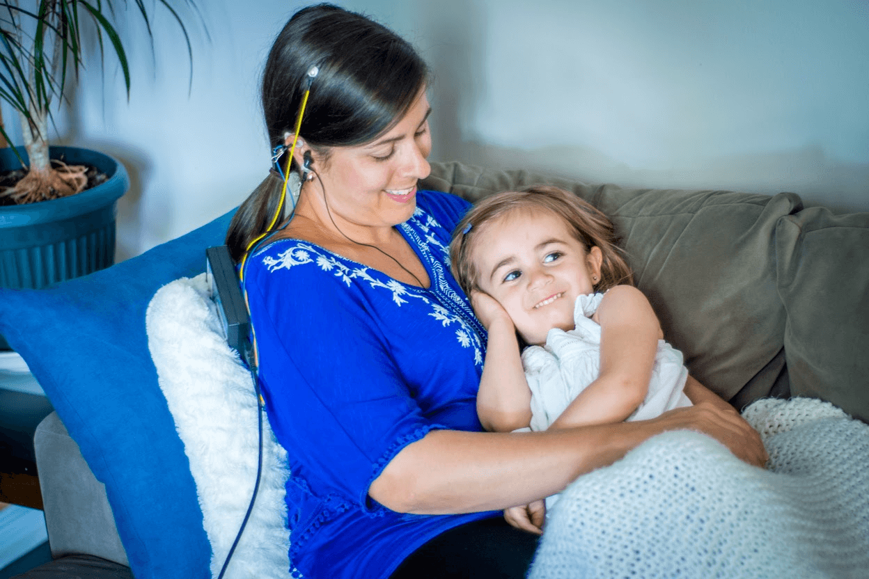 Photo of women having a neurofeedback session while holding a little girl and both are smiling.