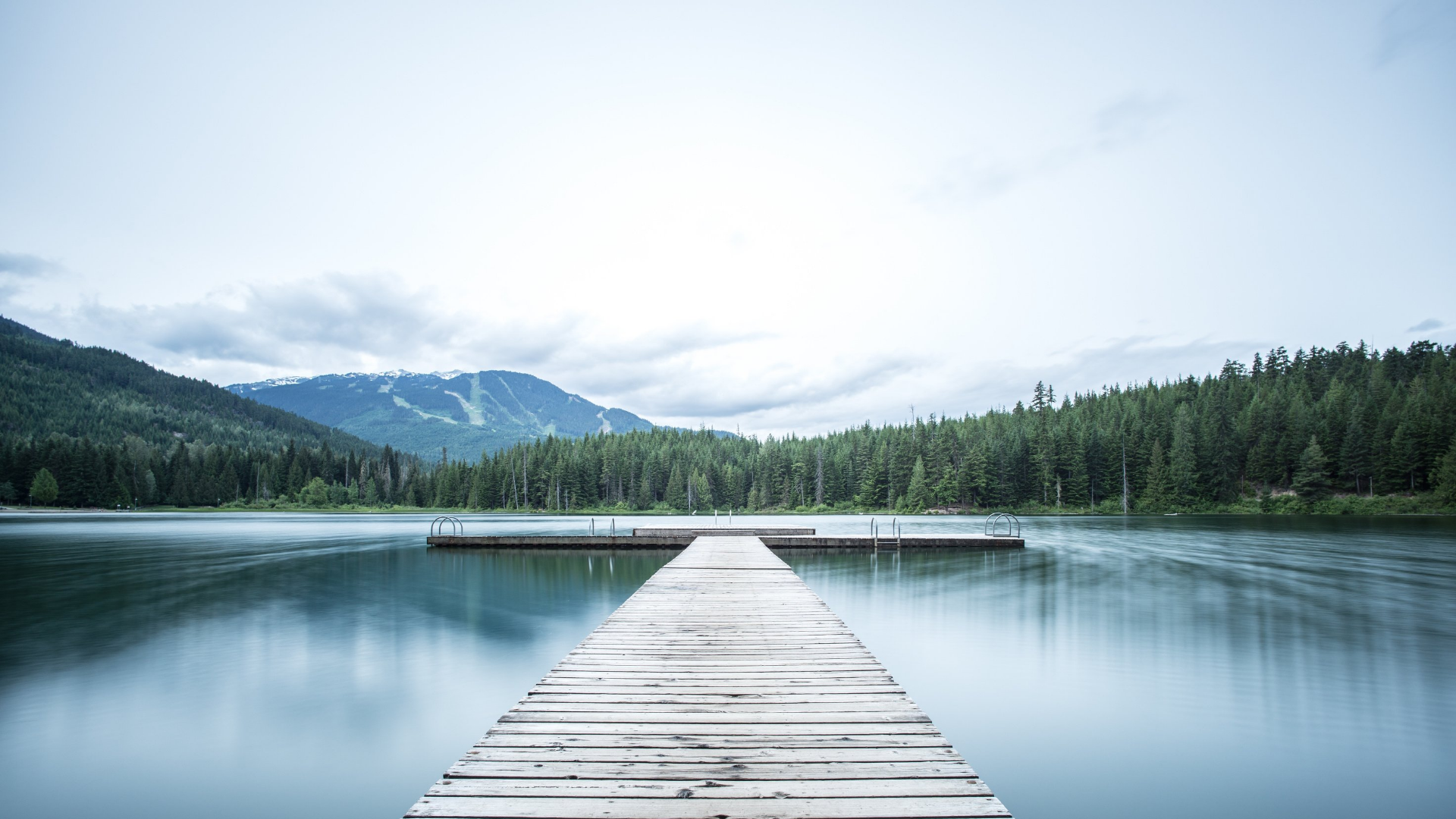 Picture of a lake with trees and mountains in the background.