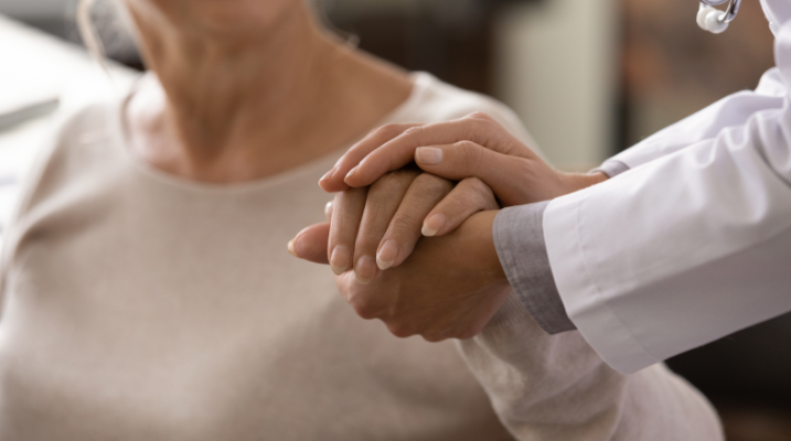 Picture of a patient holding hands with a doctor but cannot see their heads.