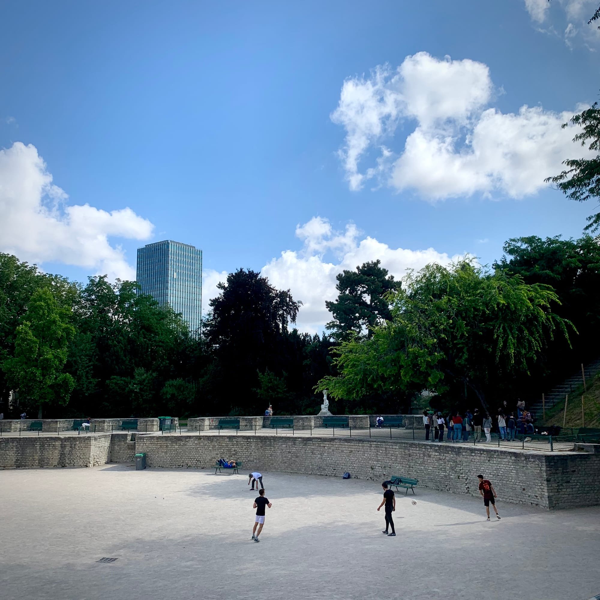 View of the Lutetia arenas: children playing soccer in the arenas, a pleasant blue sky. In the background: the Zamanski tower on the Jussieu campus.
