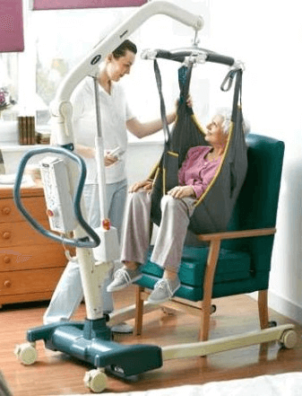 Image of a carer assisting an older woman using a sling and hoist