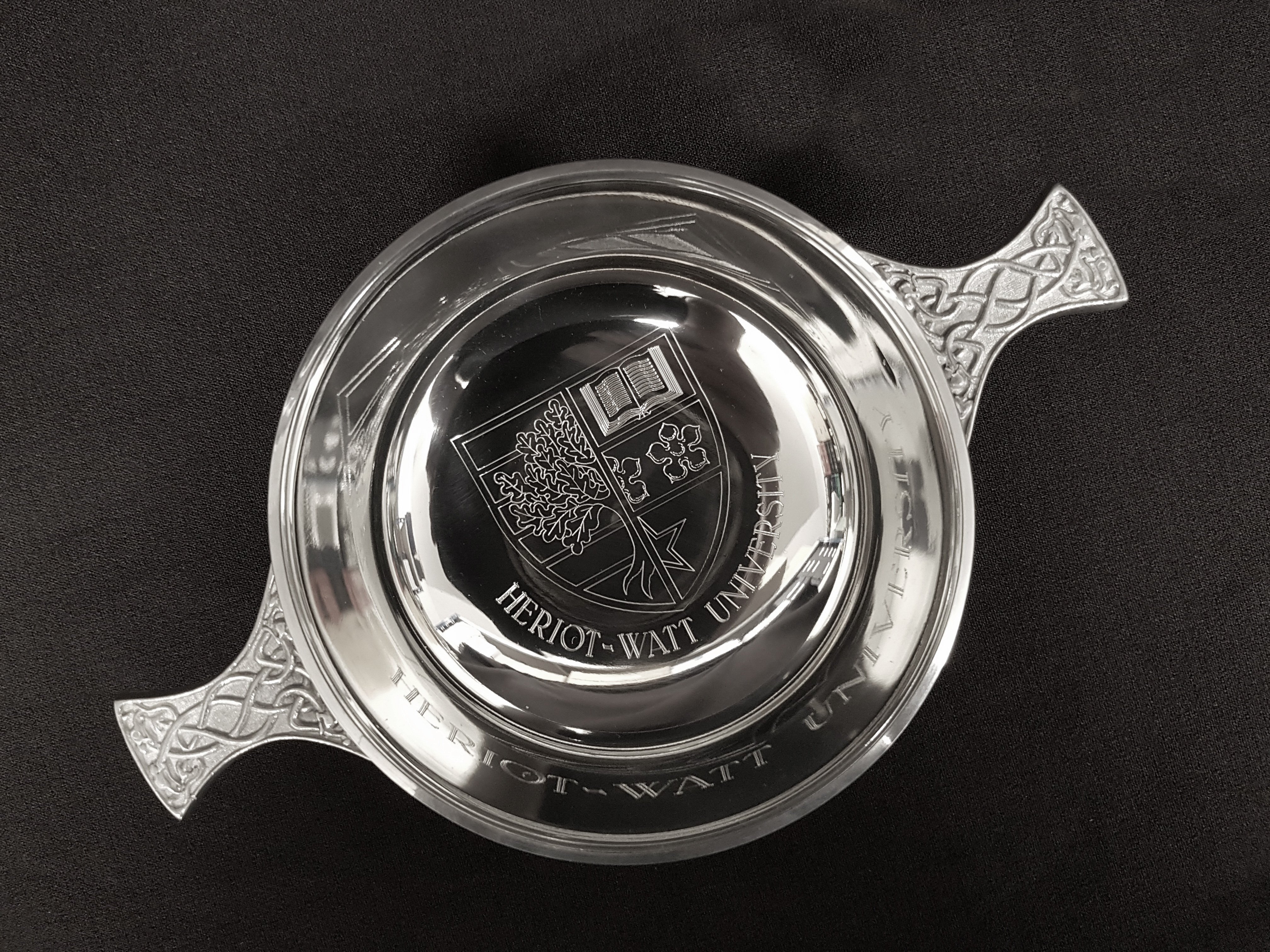 polished pewter quaich with engraved university crest in centre of bowl