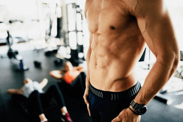 Attractive male torso in gym flexing abs