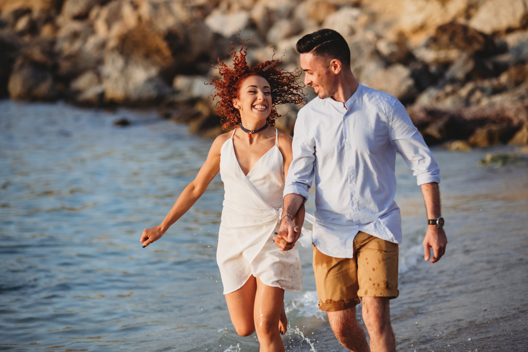 Happy couple running at a photo shoot on a beach in Paradise Bay