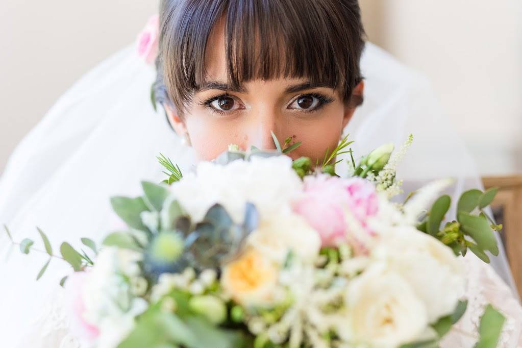 Mariée maquillée avec des yeux en amande et un bouquet de fleurs de mariée romantique