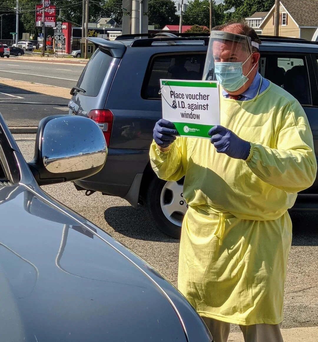 Kevin in the parking lot with a sign for a patient taking a COVID19 test