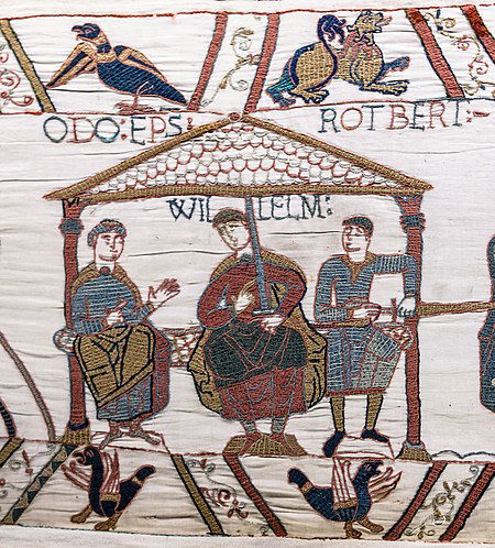 Image: a scene from the Bayeux Tapestry showing Robert (Rotbert), Count of Mortain (right) sitting to the left of his half-brother William, Duke of Normandy. Robert's full brother Odo (Odo Ep[iscopu]s, "Bishop Odo") sits to William's right, implying his seniority. (From Wikipedia, October 2021)