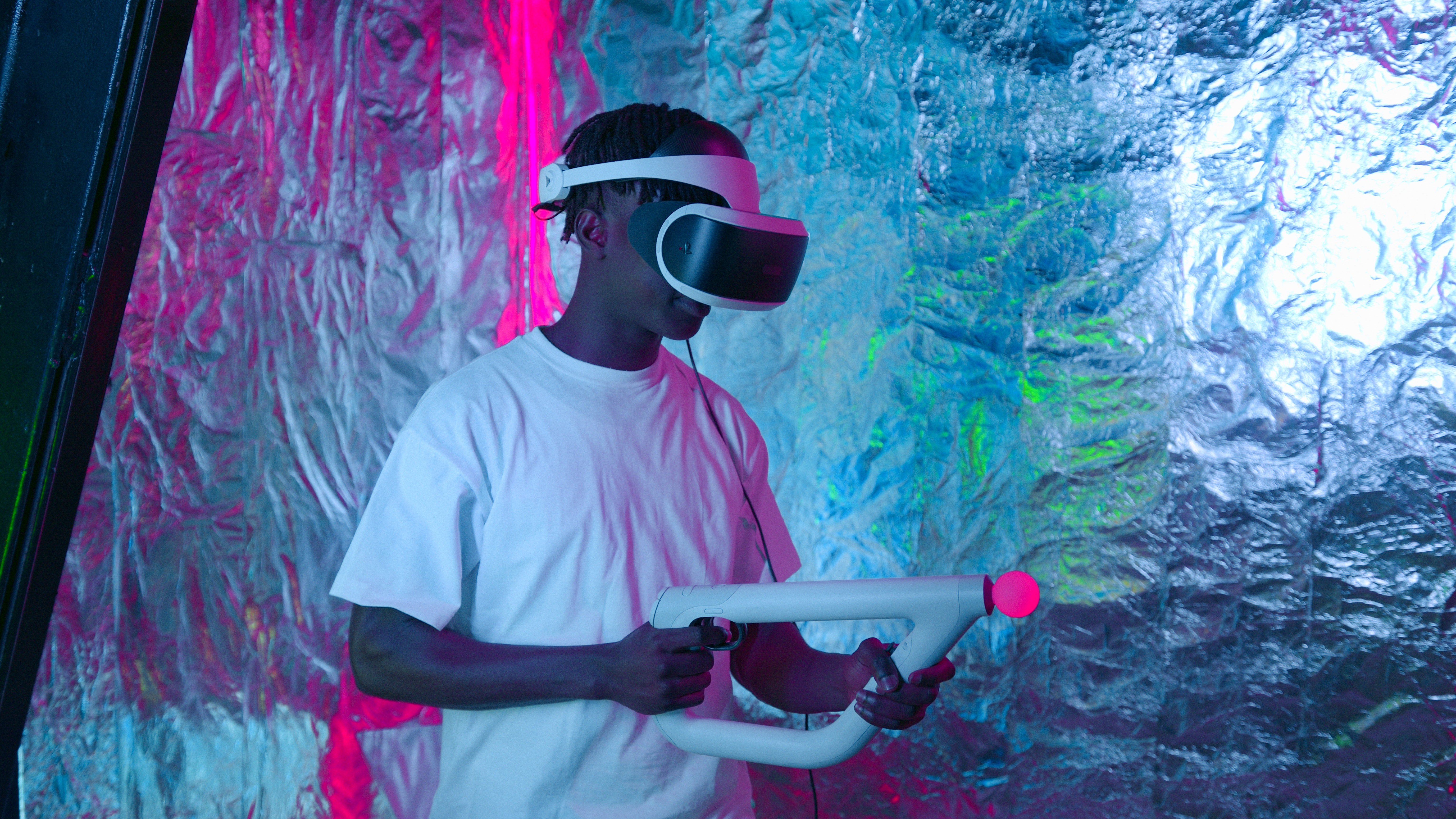 A young man using virtual reality headsets and a gun to play in the metaverse