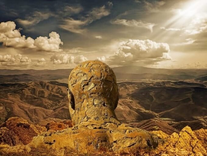 A mountain shaped like a reverse aspect of a male head and shoulders surrounded by mountains and far reaching views over a barren landscape symbolizing a god
