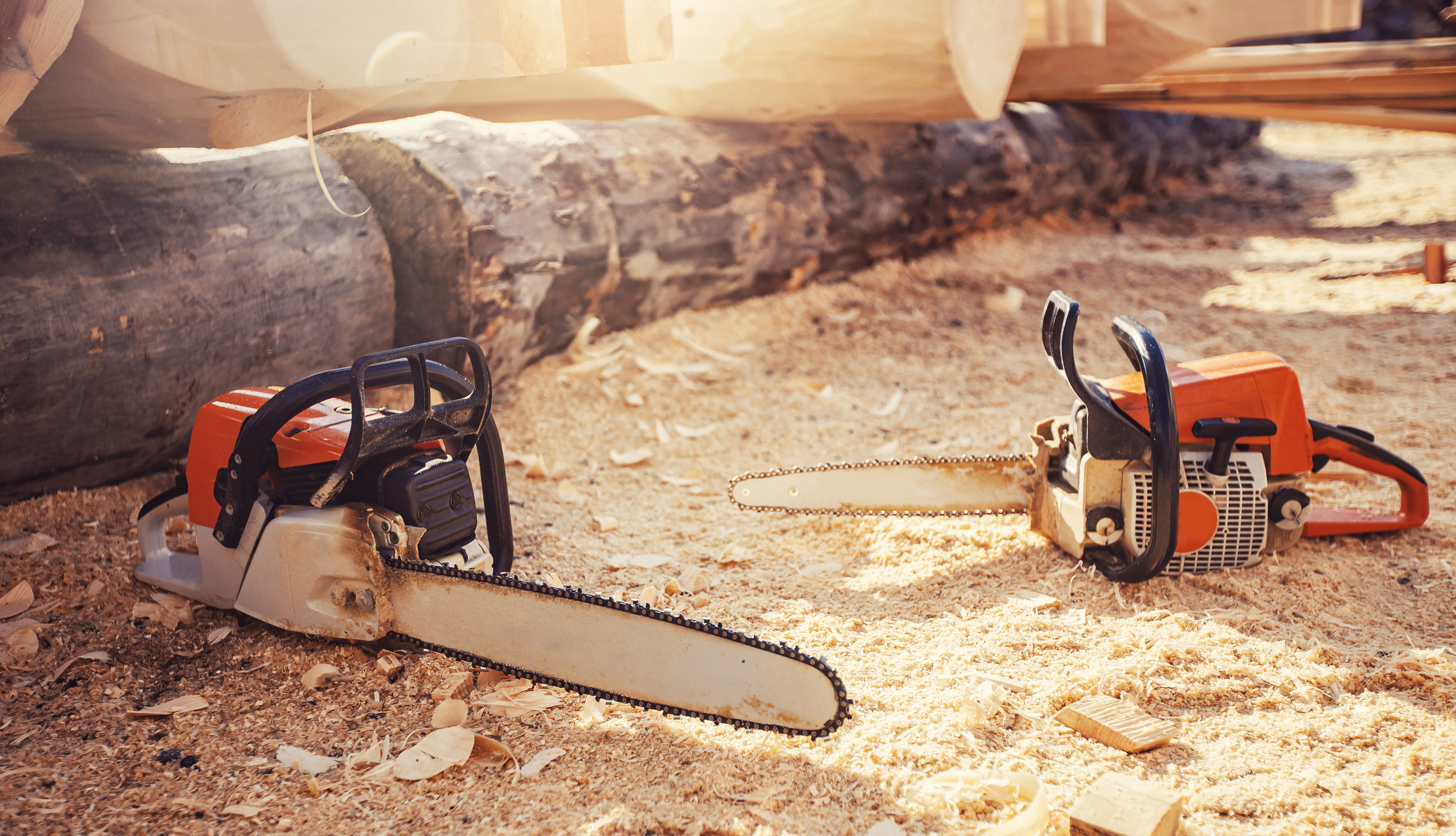 Two chainsaws sitting on the ground next to eachother