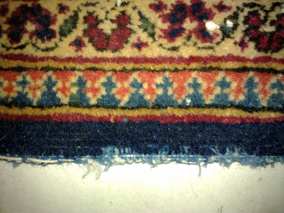 שטיח פרסי קשן עם קנטים שחוקים לגמרי קרוב להיפרם השטיח.