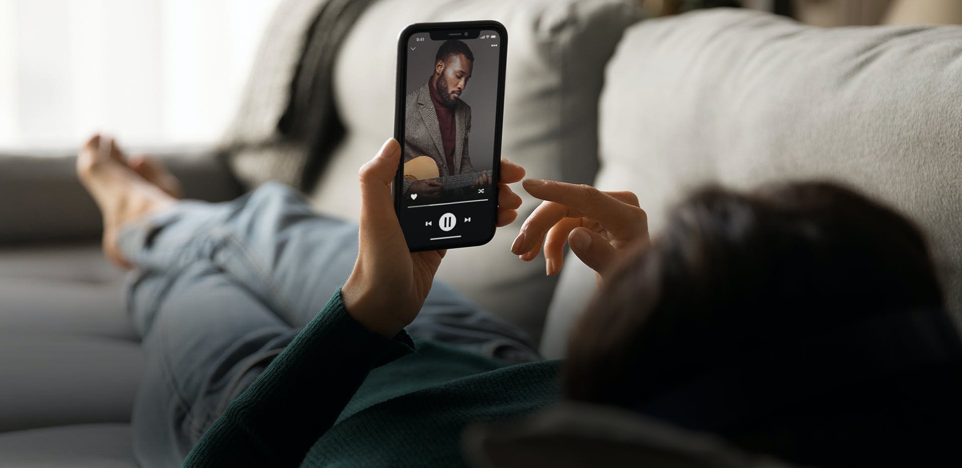 אישה שוכבת על ספה עם טלפון נייד ביד ואפליקציה יעודית ששולטת על רסיבר