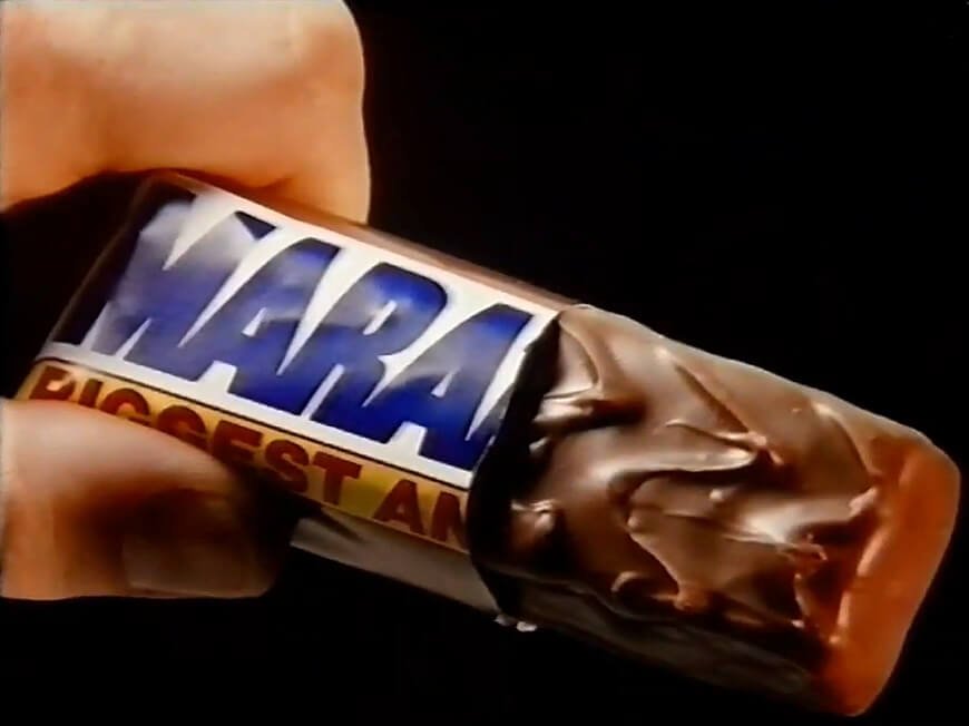 Marathon chocolate bar being held between thumb and forefinger, with black background