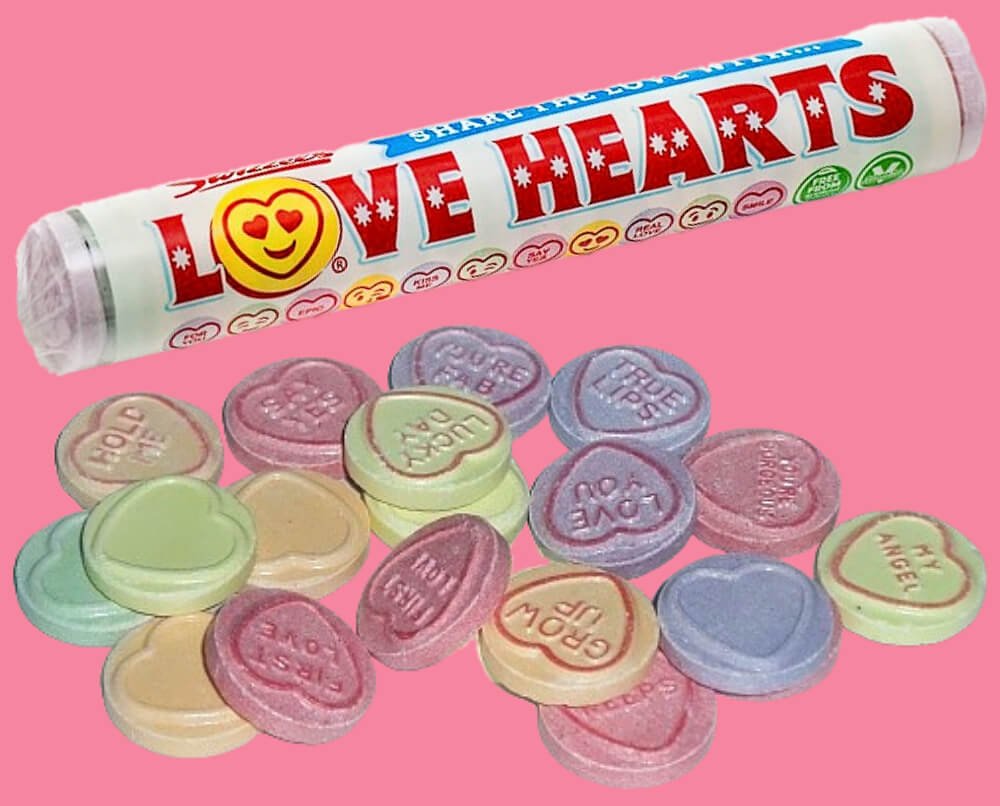 Tube of Swizzels Love Hearts with loose sweets and romantic pink background