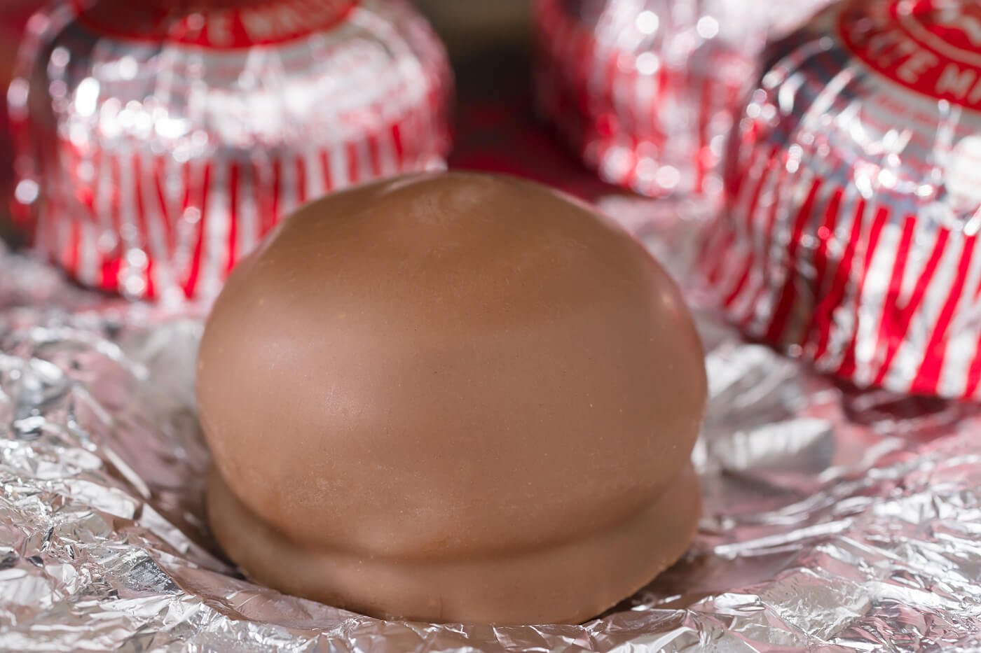 Close-up of an unwrapped Tunnock's Teacake, with wrapped teacakes in the background.
