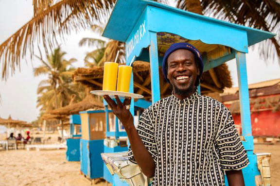 Smilende person som servere kalde drikker i Gambia