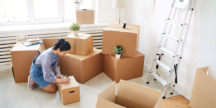 Woman Packing For Moving House and Labelling Boxes